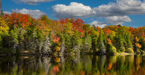 Adams reservoir in Woodford state park is surrounded by trees showing brilliaant fall colors, near...