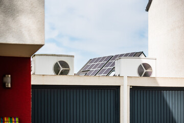 Wärmepumpe auf einem Garagendach eines Neubaugebiets, im Hintergrund sind Solarpanele auf Hausdächern montiert, Monheim am Rhein, NRW, Deutschland