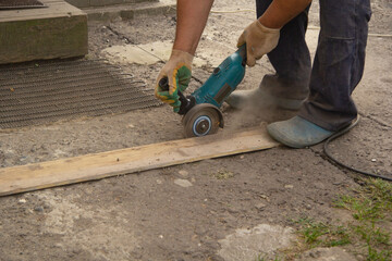 Saw a grinder in the hands of a man. sawing wooden boards