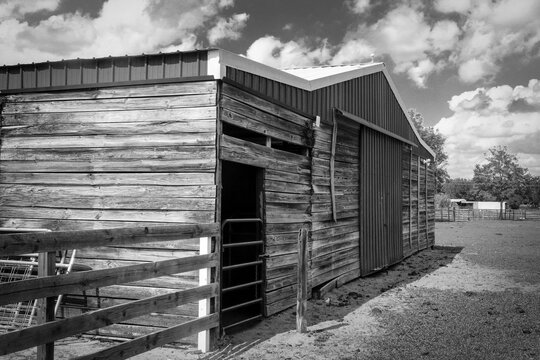 Old barn on a farm in Central Florida next to a cloudy sky shown in black and white