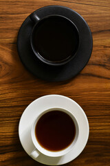 Taza blanca y negra, Café y te negro sobre una mesa de madera.