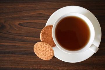 Galletas sin Gluten y taza de te negro en una mesa de madera, espacio para texto al lado izquierdo.