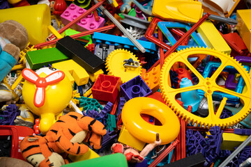 Fototapeta na wymiar An abundance of toys in the children's room, a lot of plastic multi-colored parts from designers, spare parts for toys, figurines and cubes.