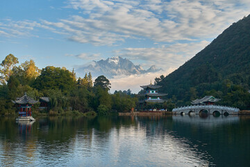 Fototapeta na wymiar The awesome landscape of The Moon Embracing Pavilion, Suocui Bridge and Black Dragon Pool against the backdrop of the Jade Dragon Snow Mountain in Lijiang, China