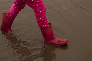 a child steps on a muddy puddle