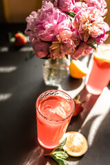 tropical and flavorful daiquiri, made with ripe fruit and a splash of liqueur from strawberries and slices of fresh fruit near a bouquet of fresh peonies