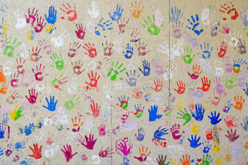 prints of children's hands in multi-colored paint on the wall