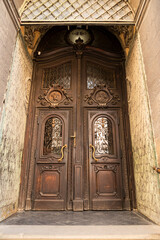 Fototapeta na wymiar Entrance street carved wooden doors with metal inserts and hinges