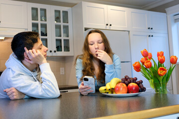 boy looks at the girl with love she is busy on the phone eating grapes and looking down social networks guy in love catching a look hope for a relationship ask for a date