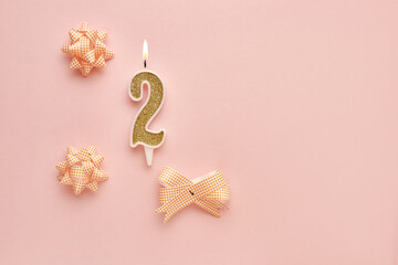 Number 2 on a pastel pink background with festive decorations. Happy birthday candles. The concept...