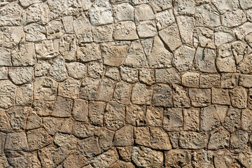 A beautiful texture of an old wall from gray and orange stones with cracks