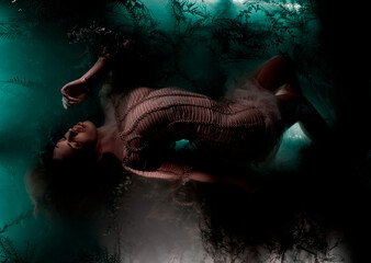 fashionable girl model lies on a swamp in algae on a dark background