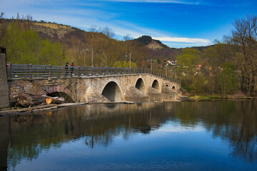 Fototapeta premium Historische Alte Burgauer Brücke über die Saale mit Spiegelung im Wasser unter strahlend blauem Himmel, Jena, Thüringen, Deutschland