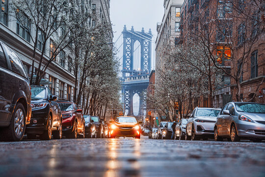 Fototapeta  Manhattan bridge seen from a narrow alley enclosed by two brick buildings on a foggy spring day.