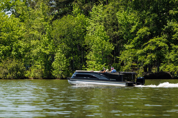 Boaters on pontoon boat enjoy summer day on Lake. Pontoon party boat cruising on freshwater lake.