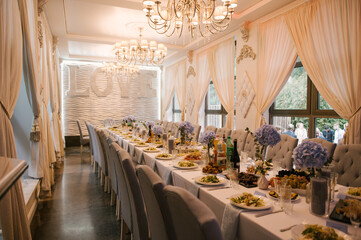 A large table is prepared for the holiday, decorated with flowers with beautiful serving and serving dishes