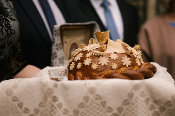 Fototapeta na wymiar decorated fresh loaf with salt lies on the table, next to the embroidered towel. Ukrainian and Russian wedding traditions. Tasty pie.