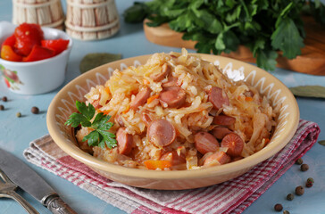 Braised cabbage with rice and sausages in a plate on a blue background