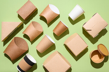 Different disposable tableware made of paper on a green background. Eco-friendly fast food dishes. flat lay. Zero waste concept.