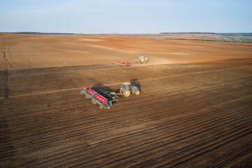 Sowing company. Agricultural machinery in the field: tractor with a seeder in the foreground, in...