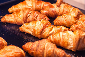 Close up of homemade delicious croissants on table in restaurant. Variety of puff pastry buns cinnamon rolls and croissant on cafe table, still life. Cooking in bakery concept. Copy ad text space