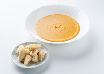 pumpkin cream soup in a white plate on a white background