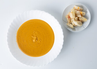 pumpkin cream soup in a white plate on a white background