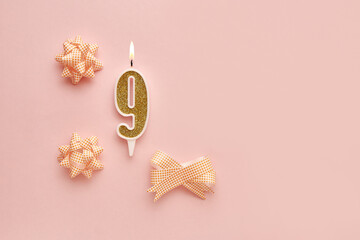 Number 9 on a pastel pink background with festive decorations. Happy birthday candles. The concept...