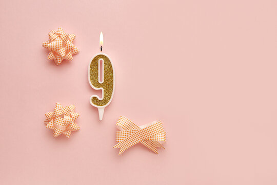 Number 9 on a pastel pink background with festive decorations. Happy birthday candles. The concept of celebrating a birthday, anniversary, important date, holiday. Copy space. banner