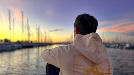 A man looks thoughtfully at the sunset on the embankment, dreams. Spain, Valencia