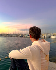 Fototapeta premium A man on the embankment meets the sunset and admires the yachts. Spain, Valencia