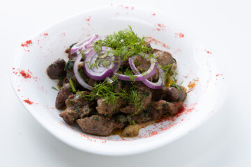 shish kebab with onions and herbs in a plate on a white background