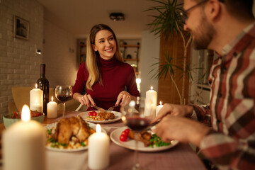 Beautiful couple having romantic dinner with candles and red wine at home