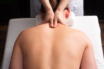 Fototapeta premium masseur massaging back and shoulder blades of young woman on massage table. Concept of massage spa treatments. Close-up