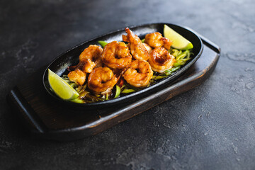 Asian cuisine. Shrimps with curry noodles. Appetizing dish on a dark background