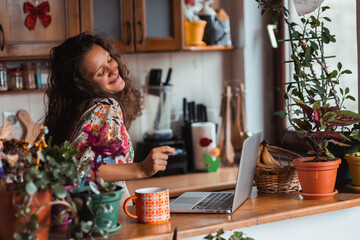 Young hippie woman with curly hair dancing around in her kitchen.