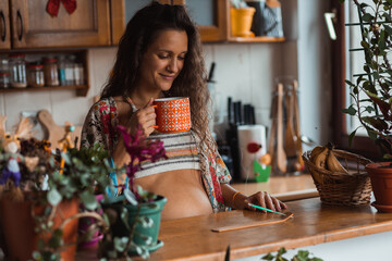 Young mother to be relaxing with a cup of tea at home.