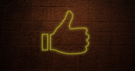 Composition of yellow neon thumbs up over brick wall