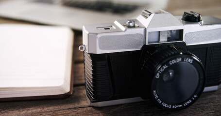 Close up of black camera and empty notebook on wooden table
