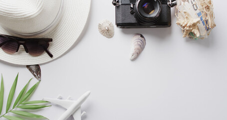 Close up of hat, sunglasses, camera, seashells and plane model on white background with copy space