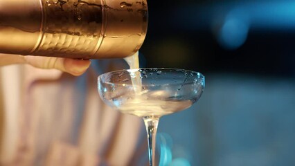Authentic professional caucasian bartender creating a cocktail drink. Experienced barman pouring alcohol beverage in glass before serving
