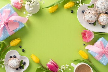 Naklejka na ściany i meble Happy Mother's Day with a stylish table setting featuring delicious cupcakes, presents, coffee cup, and tulips arranged in a top view on a pastel green background with an empty space for greeting