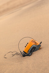 Vintage technology: old yellow walkman personal stereo cassette player resting on the sands of the...