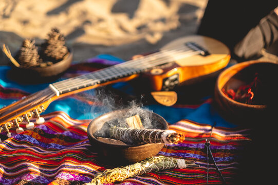 Mystical andean journey: peruvian blanket, charango, crystals and burning holy wood incense in the desert sand