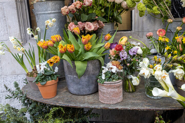 Red tulips, white daffodils and roses in a vase as a decoration of the entrance to a flower shop