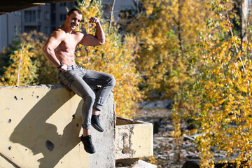 Serious Muscular Model Sitting Outdoors in Ruins