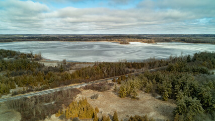 An aerial drone shot of a train track going over a frozen lake in the winter