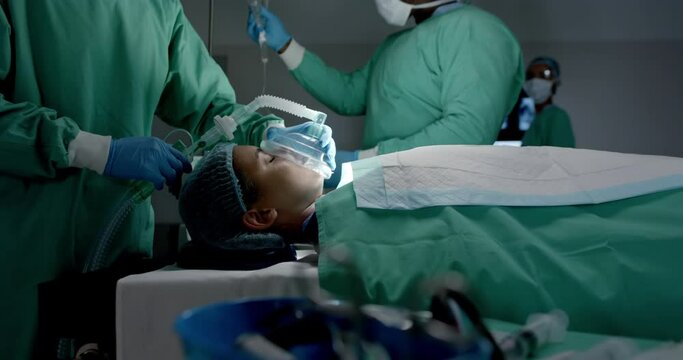 Diverse surgeons with face masks using oxygen mask on patient in operating room in slow motion