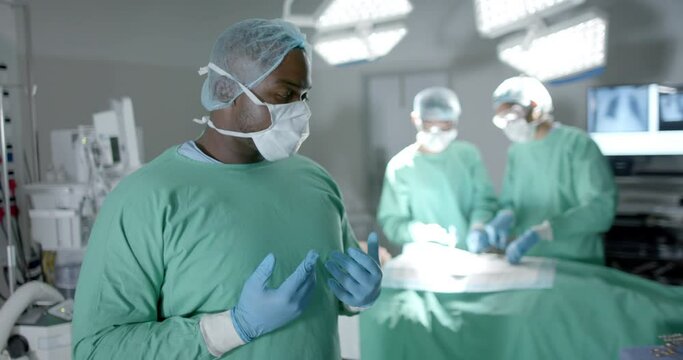 Portrait of diverse surgeons with face masks during surgery in operating room in slow motion