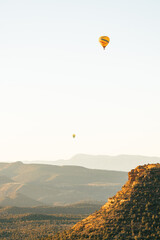 Two hot air balloons high and low taking flight in early morning in Sedona Arizona.